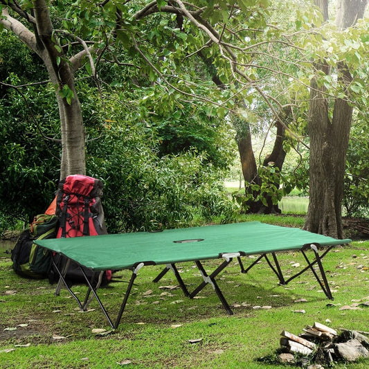 The double camping cot bed set up outdoors with camping gear nearby