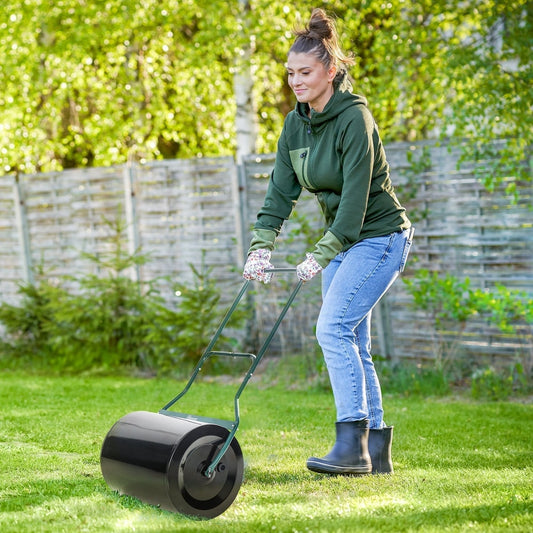 Woman using the garden lawn roller to flatten grass in a sunny garden