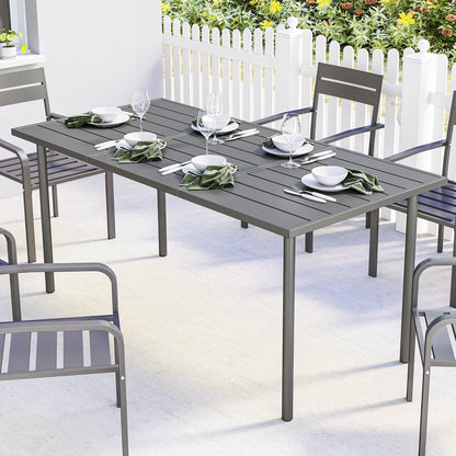 A rectangular outdoor dining table set for six people with plates, glasses and cutlery on a patio