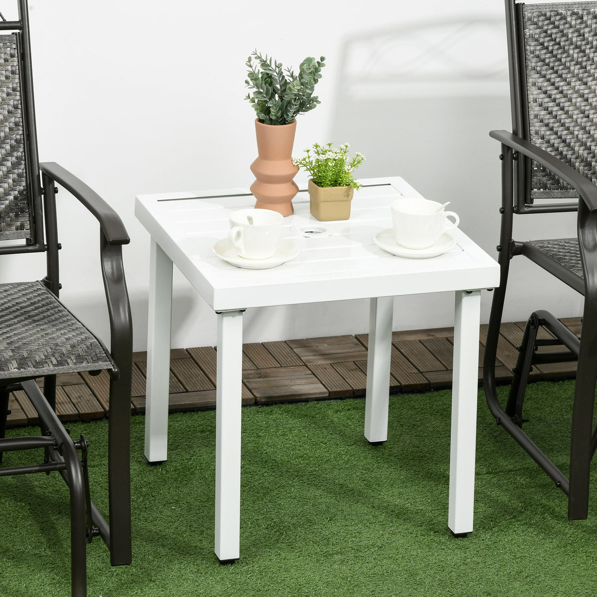 The garden table placed between two chairs on a patio with cups and plants on the surface