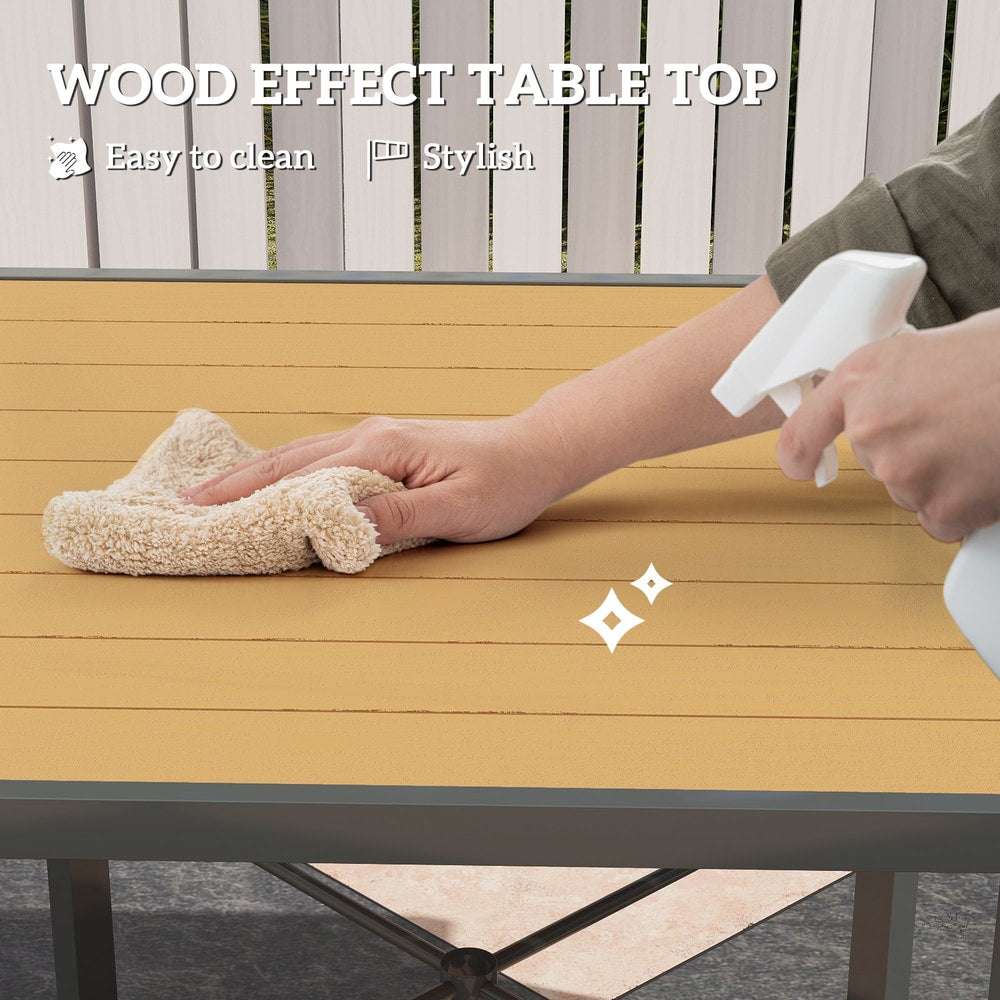 Close up of a hand cleaning the wood effect top of a square outdoor dining table with a spray bottle