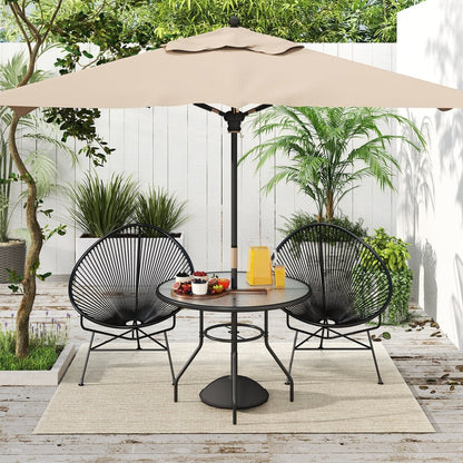 A round garden table with a glass top, set up with two chairs and a parasol in a sunny outdoor patio setting