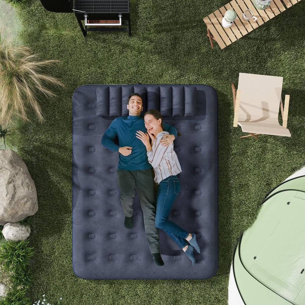 A couple relaxing on the blue inflatable camping bed outdoors on grass