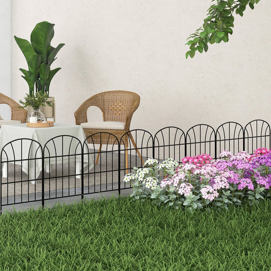Black metal picket fence panels bordering a flower bed in a garden setting