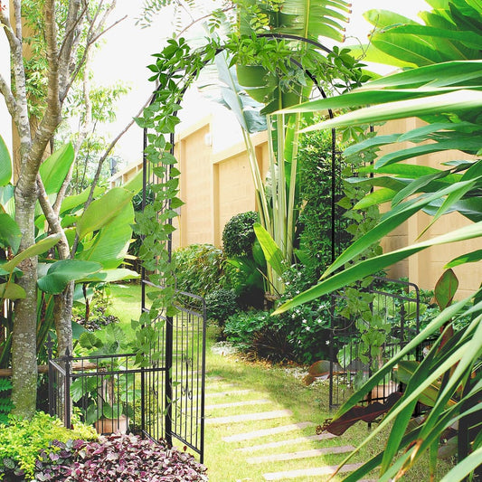 The garden archway with double doors set up in a lush garden with climbing vines