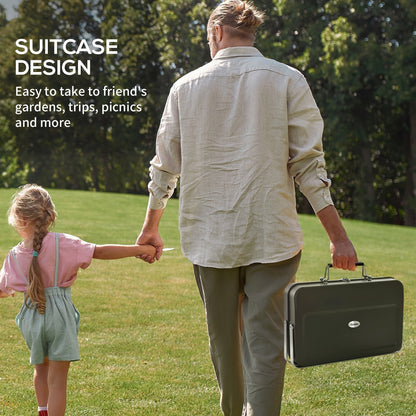 A man and child walking in a park carrying the portable charcoal grill in its case