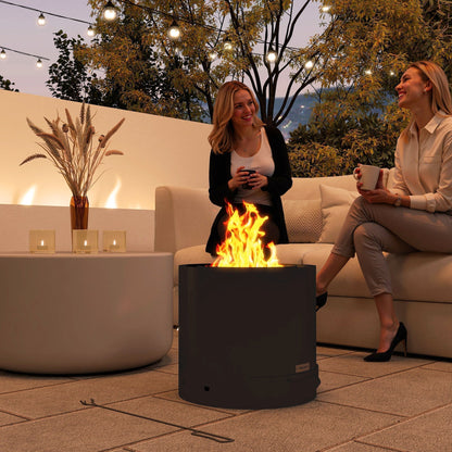 The outdoor fire pit in use at night, with two people sitting on a sofa nearby, enjoying the warmth and light