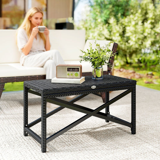 The garden table is set up on a patio with a woman sitting on a sofa in the background