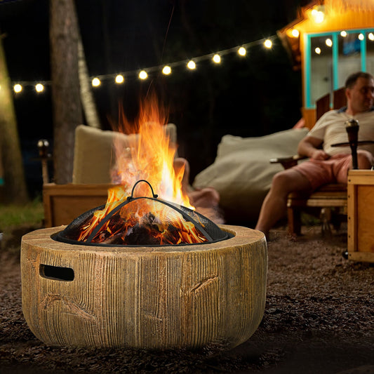 the outdoor fireplace in use at night with a fire burning and people relaxing nearby