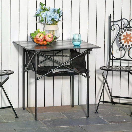 The folding camping table set up on a patio with two chairs and fruit in a bowl