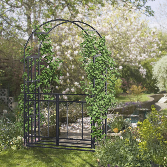 The metal garden arch with double gates is covered in green climbing plants in a garden setting