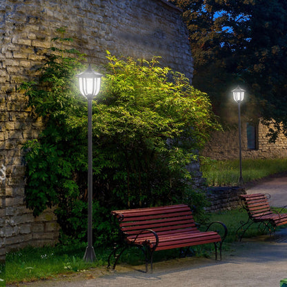 The solar post lamp stands tall in a garden setting at night, casting a warm glow on the pathway