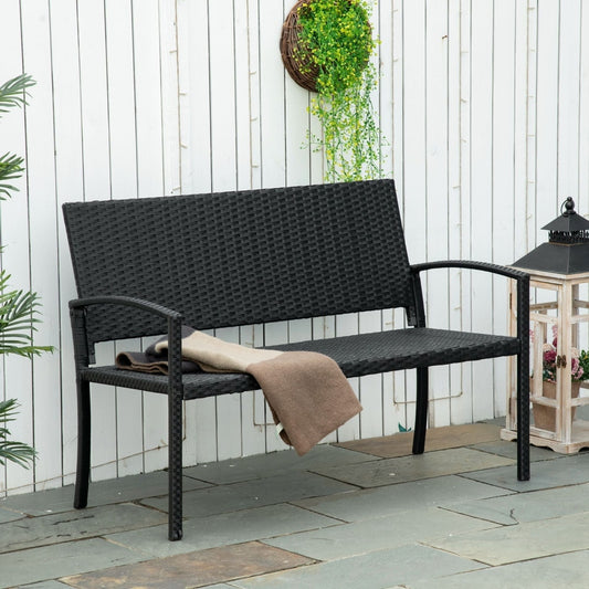 The rattan garden bench placed on a patio with a folded blanket on the seat