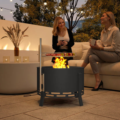 The fire pit in use on a patio at night with two women sitting nearby on a sofa