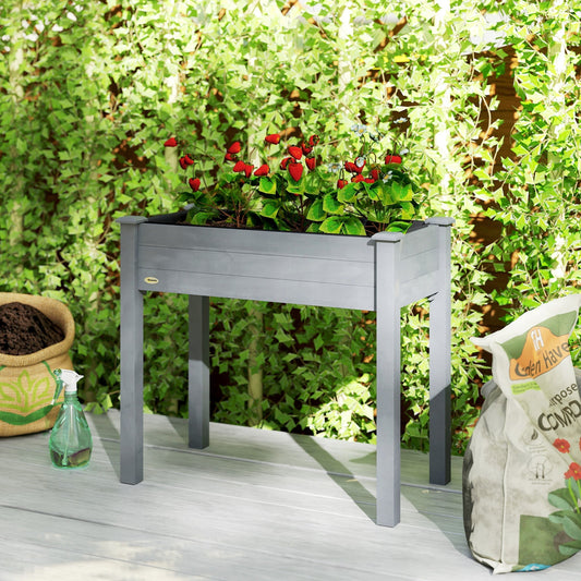 The wooden raised garden bed filled with red strawberries and green leaves, set outdoors