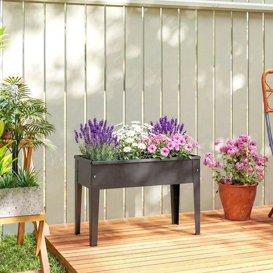 A black metal raised garden bed on legs filled with colourful flowers on a wooden deck