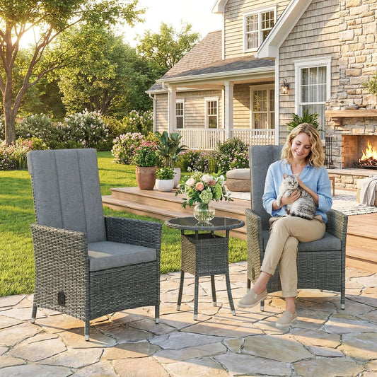 A woman relaxing in a grey rattan garden chair next to a small table on a patio