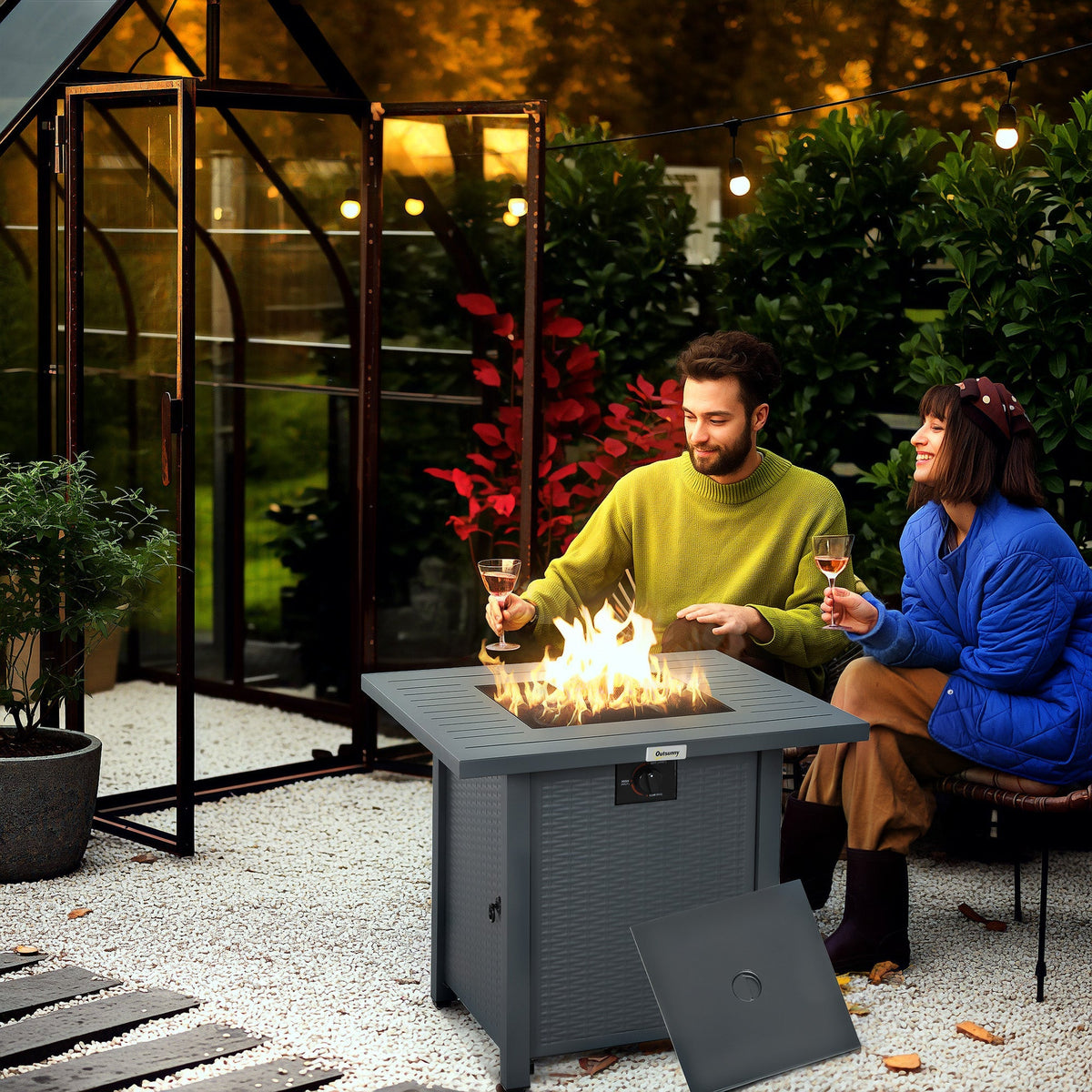 Two people enjoying a fire pit table in a garden at dusk