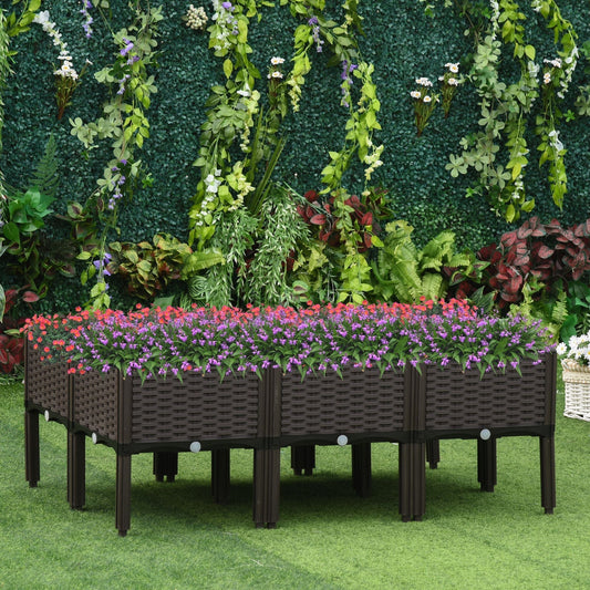 The elevated planter boxes arranged in a garden setting with a green hedge in the background
