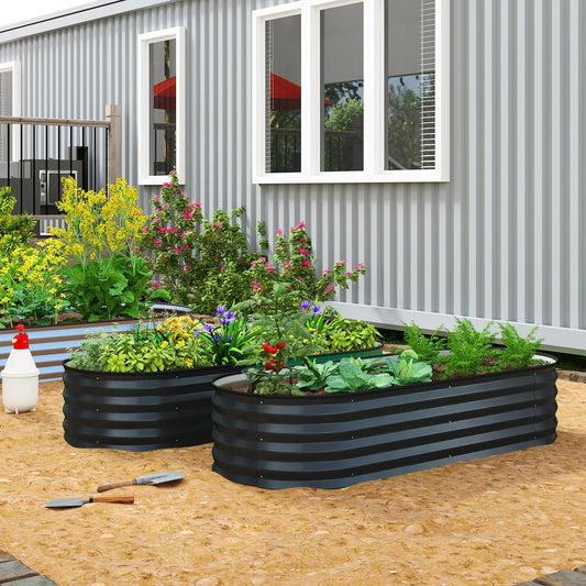 Two dark grey steel planters filled with plants in a garden setting next to a building