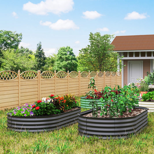 Two dark grey steel planters filled with soil and plants standing on a grassy lawn