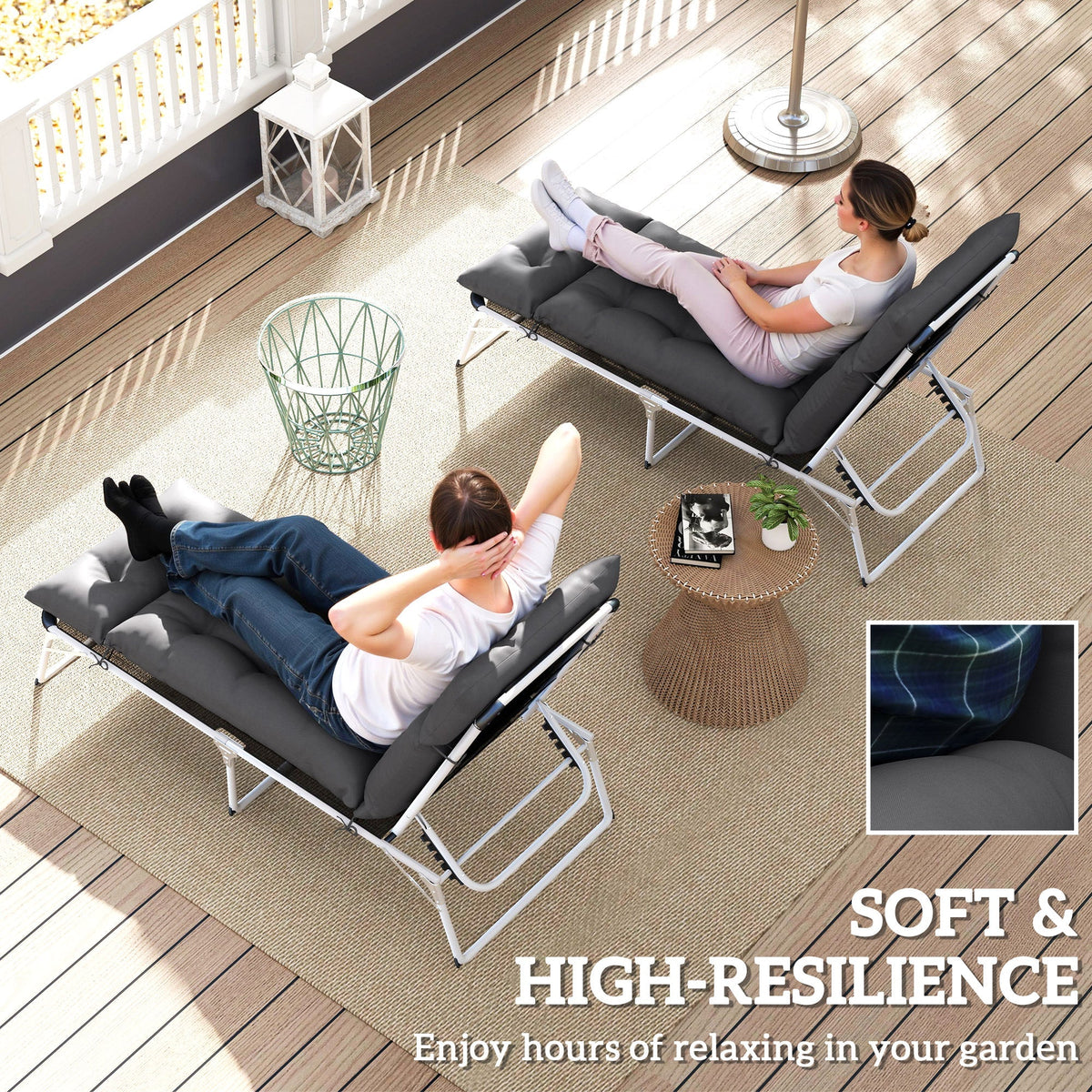 Two people relaxing on sun loungers with dark grey cushions on a patio