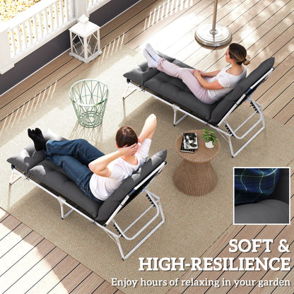Two people relaxing on sun loungers with dark grey cushions on a patio