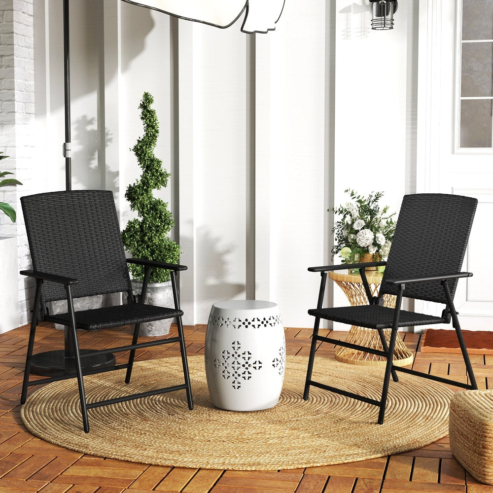 The dining chairs placed on a circular rug on a patio with a small white table between them