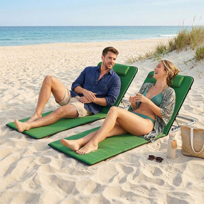 A man and woman relaxing on green metal frame beach chairs on a sandy beach