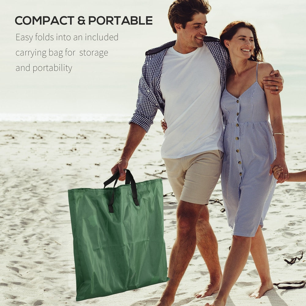 Couple carrying a green metal frame beach chair in a carry bag on the beach