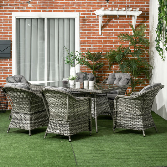 The rattan dining set arranged on a patio with a brick wall background