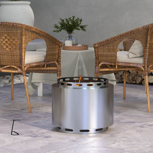 The portable fire pit burning on a patio between two wicker chairs with a table in the background