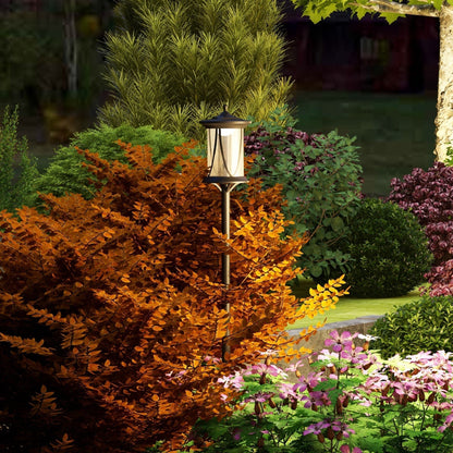 The garden lighting lamp post standing amongst colourful bushes and flowers at dusk