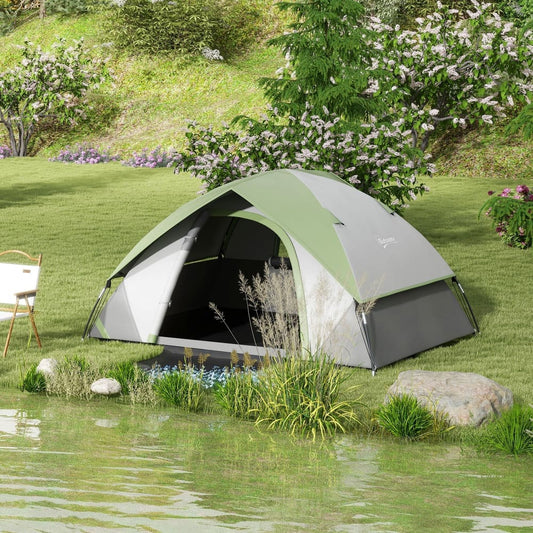 The green and grey camping tent pitched by a lake with trees and bushes in the background