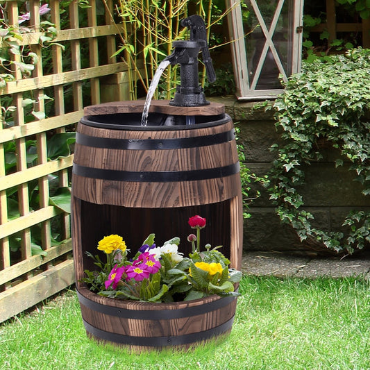 The wood barrel patio water fountain electric pump garden decorative ornament in use with flowers in the planter