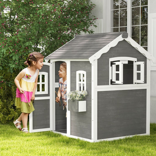 The wooden playhouse standing on a lawn with two children playing inside and outside