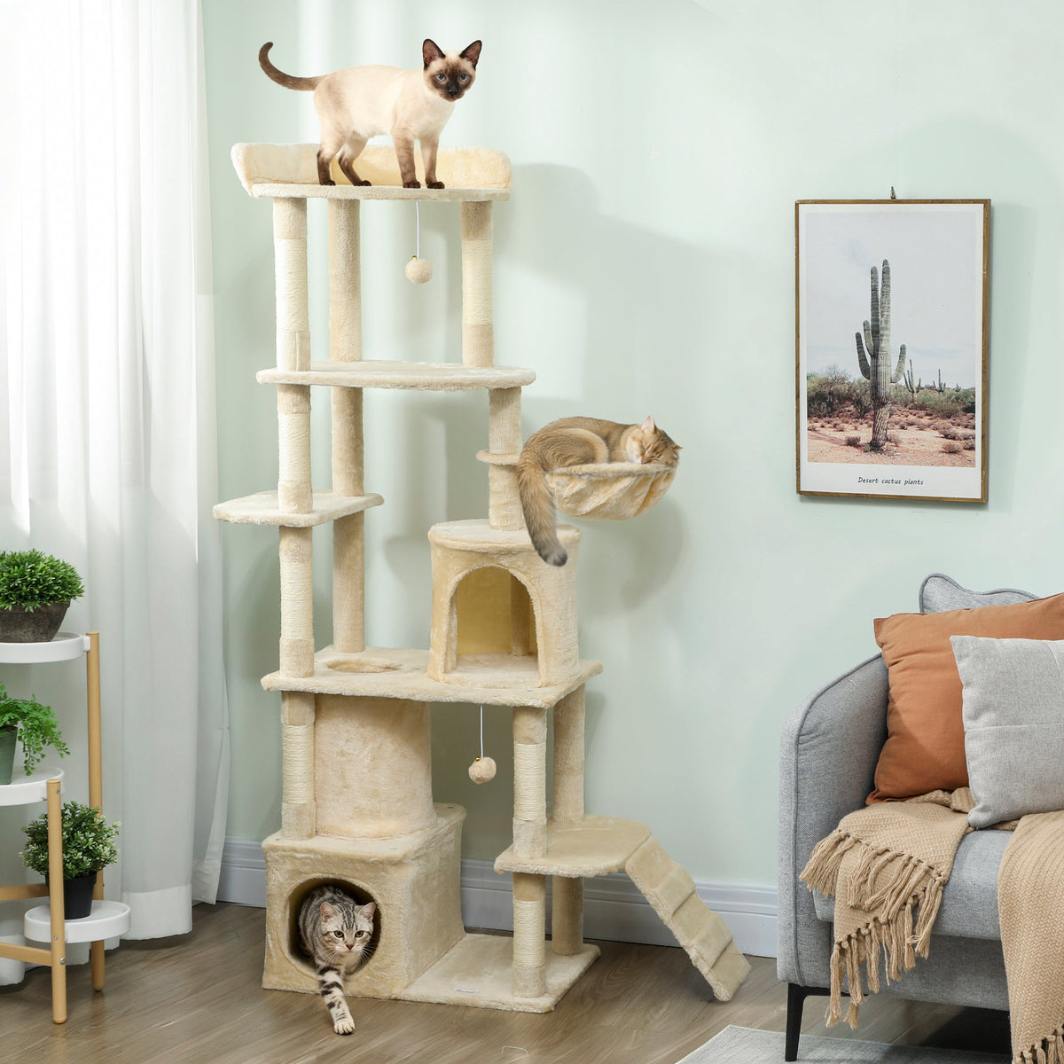 The beige cat tree standing in a living room with three cats playing and resting on the levels