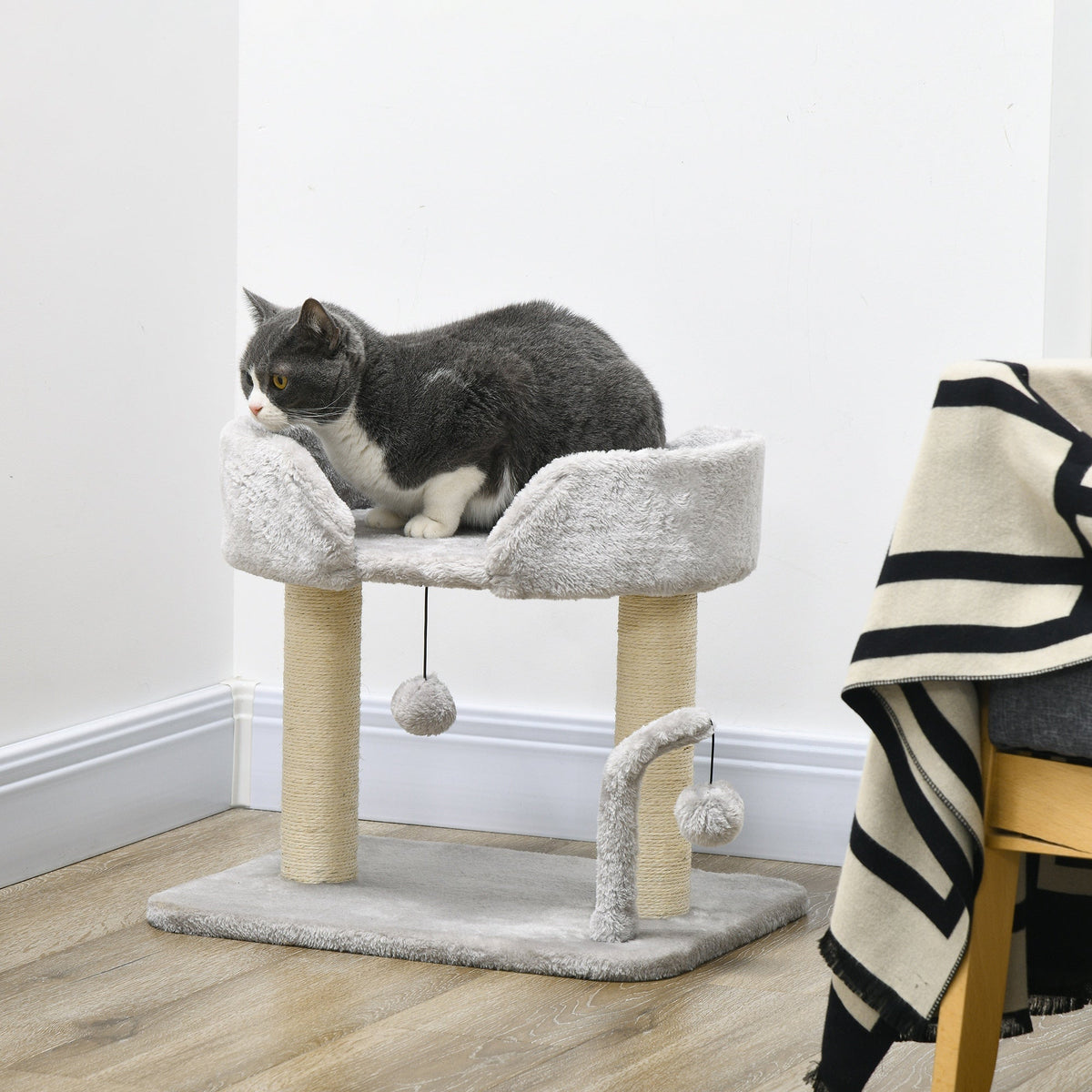 The cat tree placed in a room with a grey and white cat sitting comfortably on the top bed