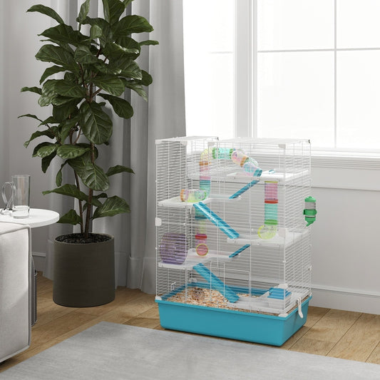 The hamster cage set up in a bright living room next to a sofa and plant