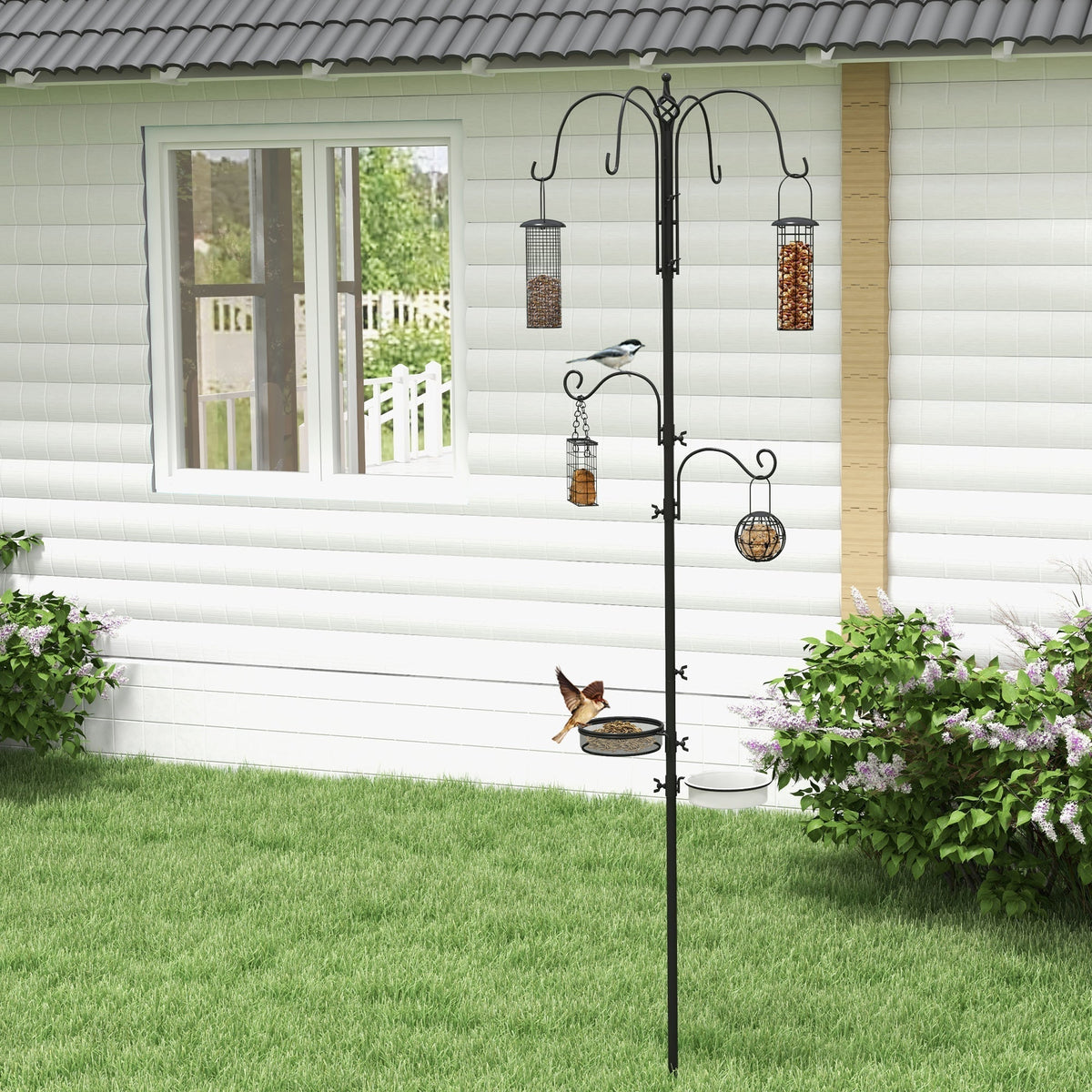 The bird feeding station standing in a garden with small birds visiting the hanging feeders