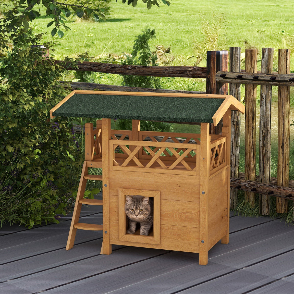 A wooden outdoor cat house with a green roof, featuring a ladder and balcony, with a cat peeking out of the doorway