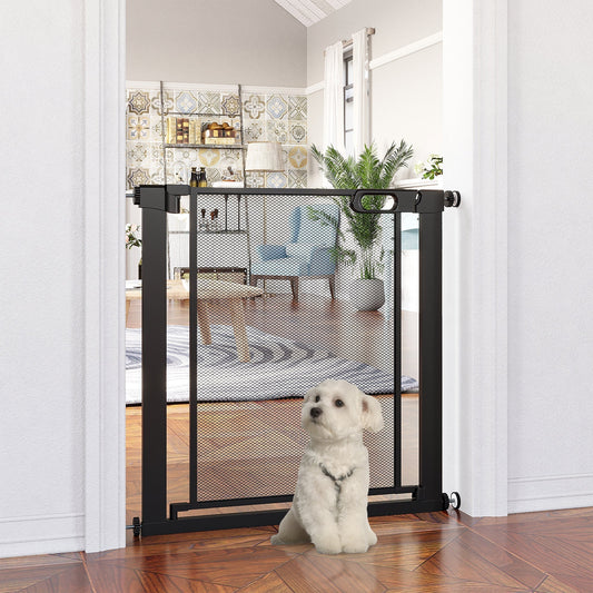 The black mesh dog gate is installed in a doorway with a small white dog sitting in front of it