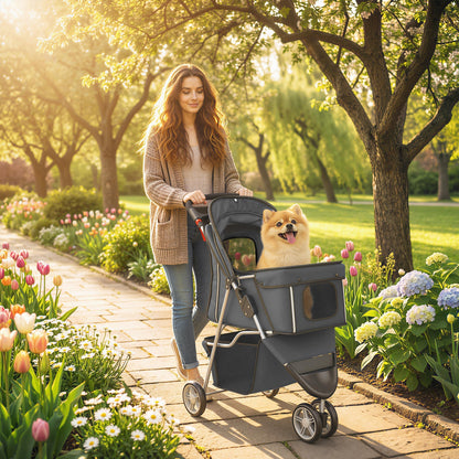 A woman pushes a dark grey dog stroller with a small dog inside along a sunny garden path