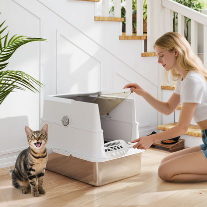 Woman cleaning the large stainless steel cat litter tray with a scoop while a cat watches