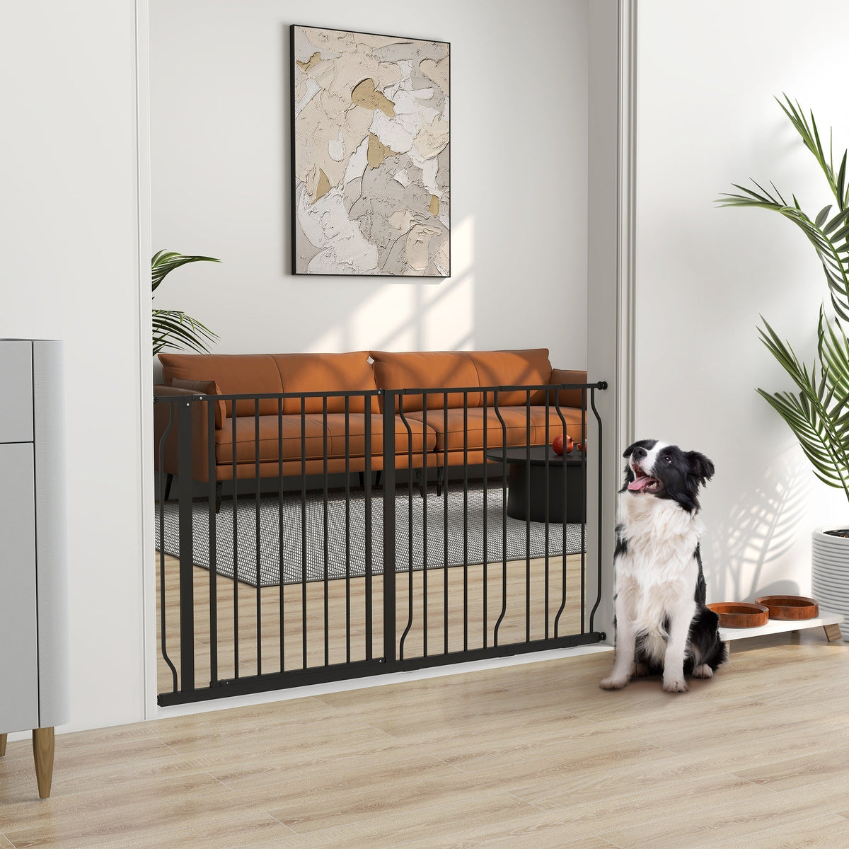The black metal dog safety gate is installed in a doorway, with a black and white dog sitting beside it