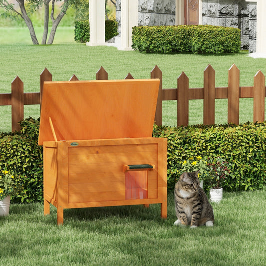 The cat house standing on a green lawn with its roof propped open and a cat sitting nearby