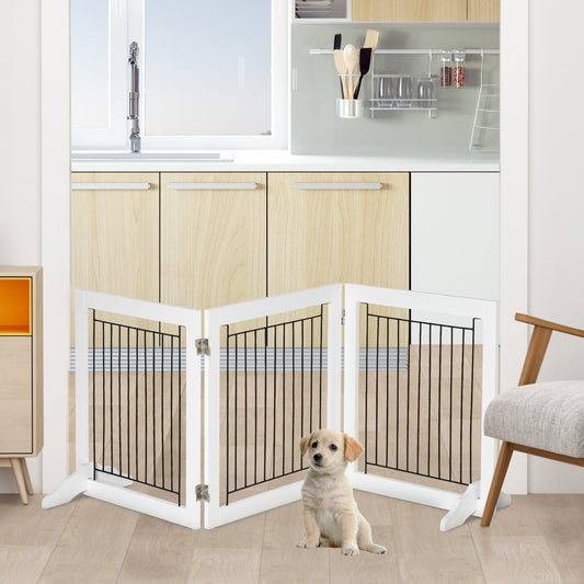 A small puppy sits in front of the white three-panelled dog gate, which is set up in a kitchen doorway