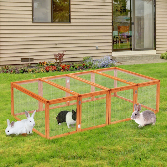 The wooden guinea pig hutch is set up on a lawn with three rabbits inside exploring the enclosure