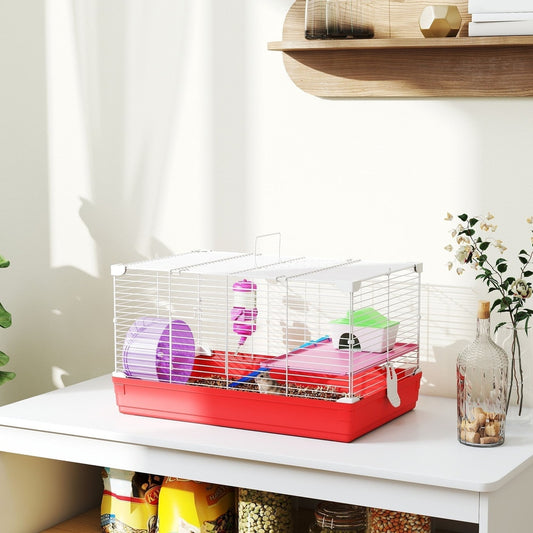 The hamster hutch is set up on a white table with some bags of pet food underneath