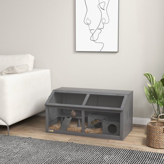 The hamster cage placed on a wooden floor in a living room next to a white sofa and a plant